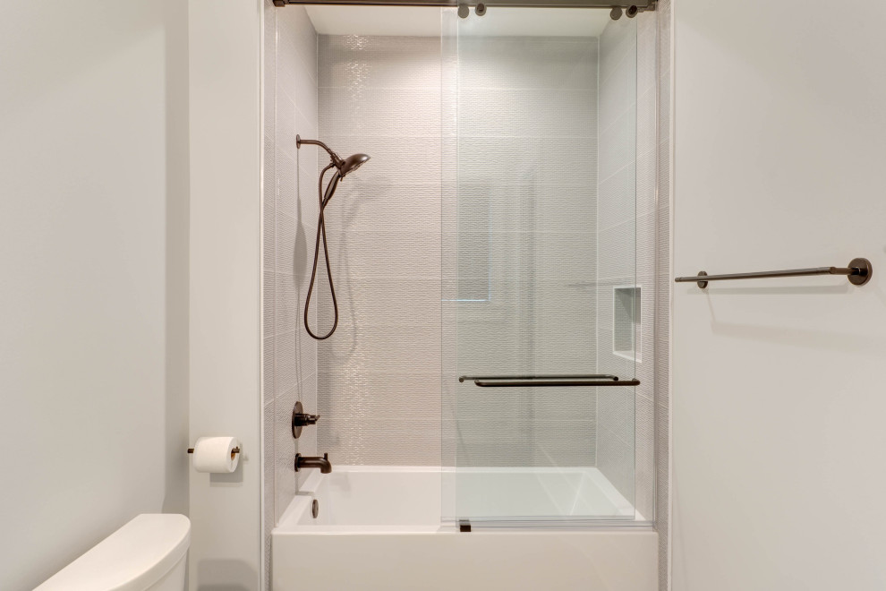 Photo of a mid-sized country kids bathroom in Atlanta with shaker cabinets, grey cabinets, an alcove tub, a shower/bathtub combo, a two-piece toilet, gray tile, ceramic tile, grey walls, porcelain floors, an undermount sink, engineered quartz benchtops, grey floor, a sliding shower screen, white benchtops, a niche, a single vanity and a built-in vanity.
