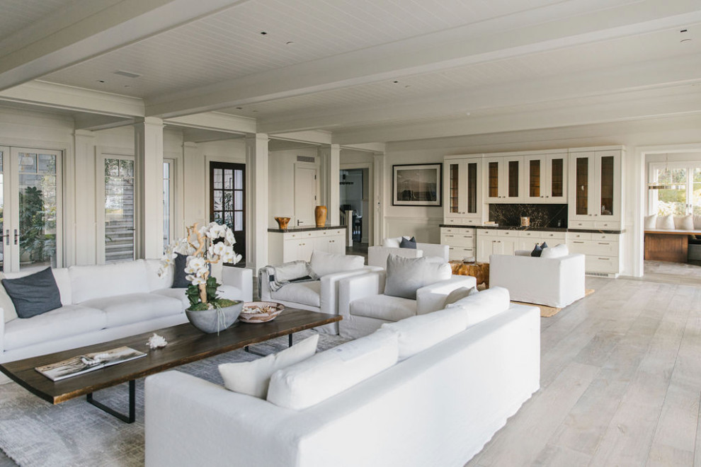 Photo of an expansive beach style formal open concept living room in Los Angeles with white walls, plywood floors, a standard fireplace, a stone fireplace surround and white floor.
