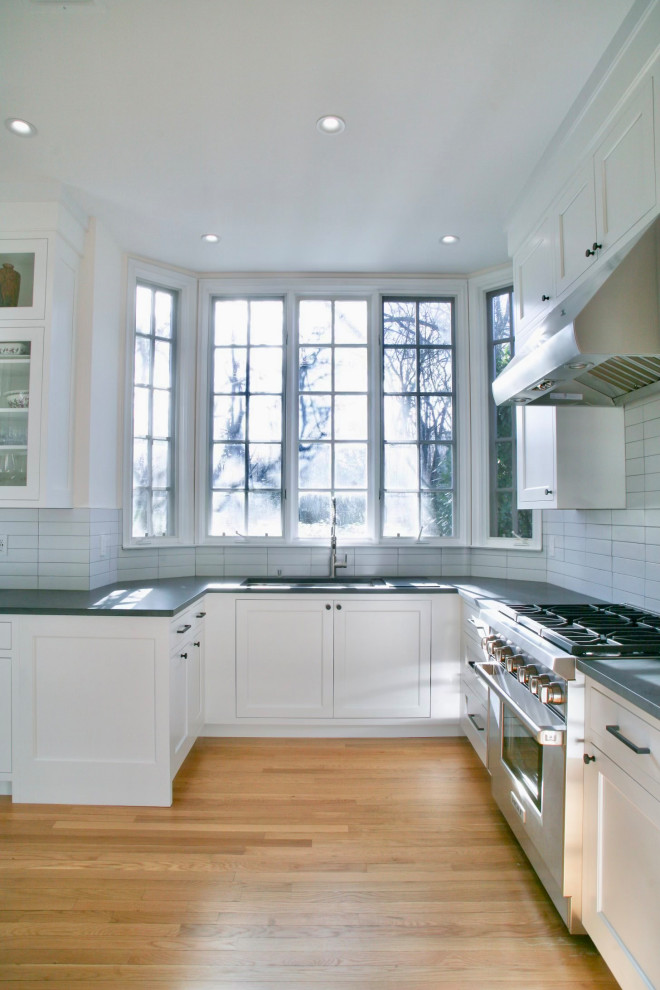 Exempel på ett stort klassiskt grå grått kök, med en undermonterad diskho, luckor med infälld panel, vita skåp, bänkskiva i kvartsit, rostfria vitvaror och ljust trägolv