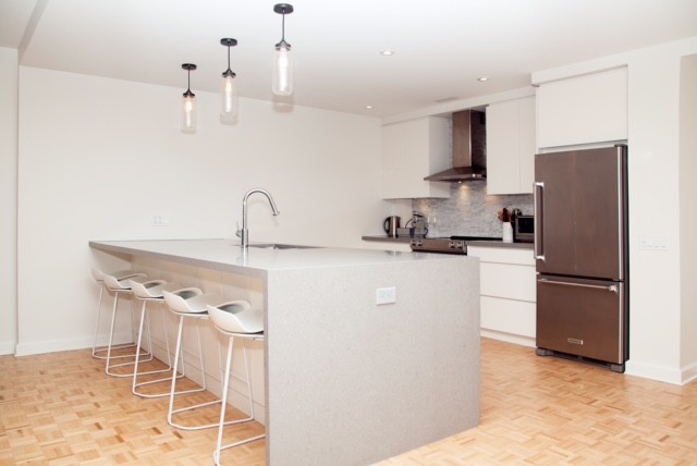 Mid-sized transitional single-wall light wood floor open concept kitchen photo in Toronto with an undermount sink, flat-panel cabinets, white cabinets, stainless steel appliances and a peninsula
