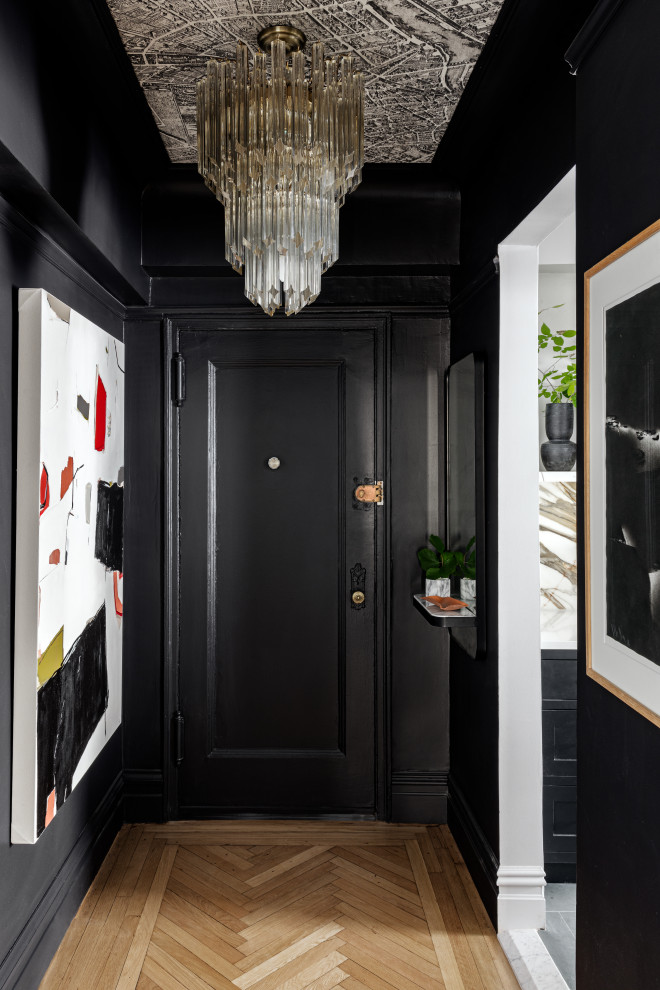 This is an example of a transitional entry hall in New York with black walls, light hardwood floors, a single front door, a black front door, beige floor and wallpaper.