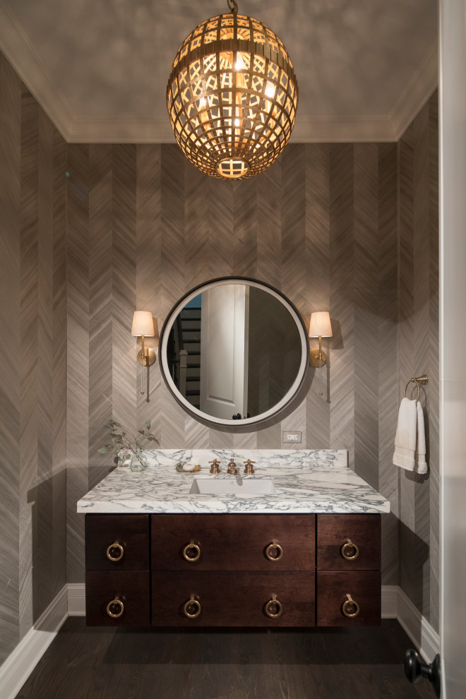Design ideas for a mid-sized traditional powder room in Chicago with flat-panel cabinets, dark wood cabinets, a two-piece toilet, grey walls, dark hardwood floors, an undermount sink, marble benchtops, brown floor and white benchtops.