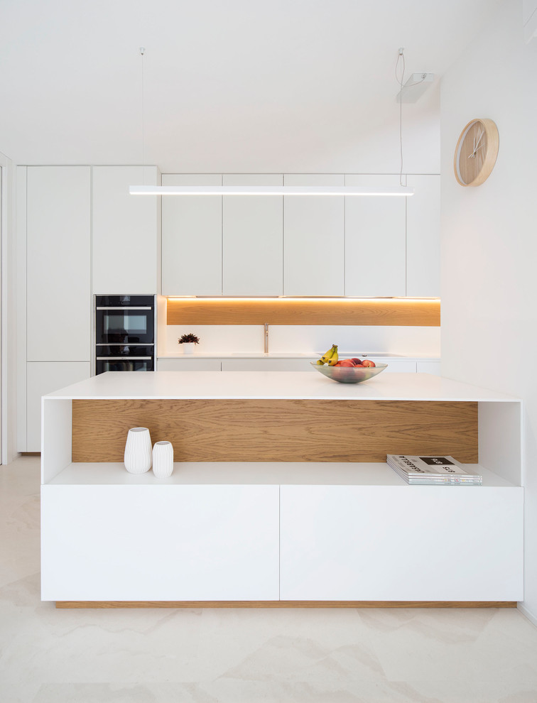 Mid-sized contemporary u-shaped open plan kitchen in Venice with with island, flat-panel cabinets, white cabinets, white splashback, white appliances and beige floor.
