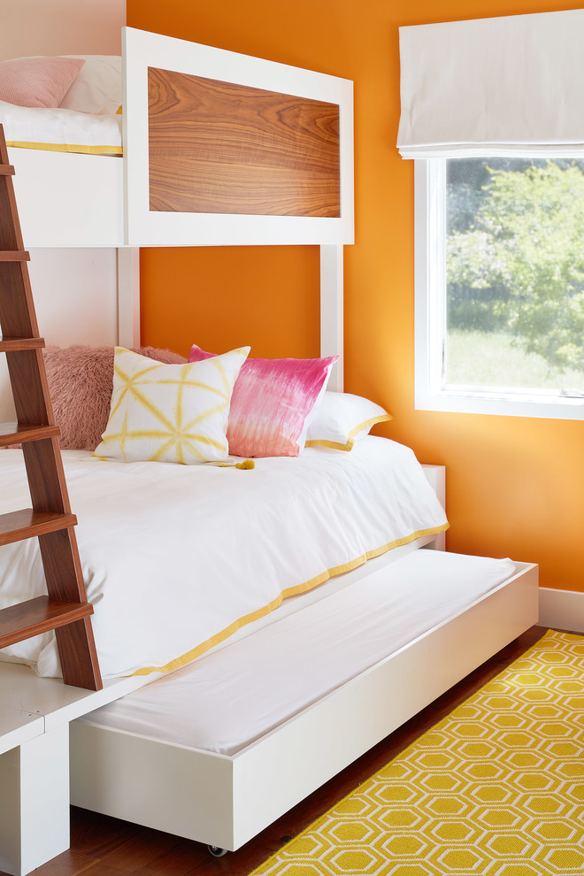 Design ideas for a contemporary gender-neutral kids' bedroom for kids 4-10 years old in San Francisco with orange walls, medium hardwood floors and brown floor.