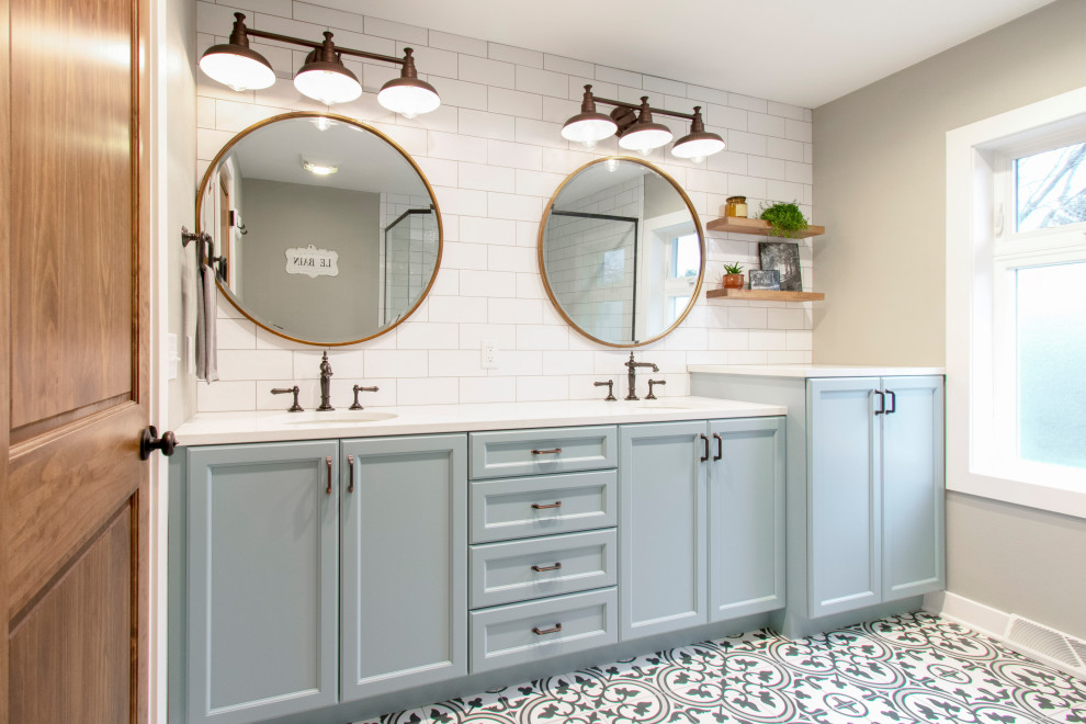 Photo of a mid-sized contemporary master bathroom in Milwaukee with recessed-panel cabinets, blue cabinets, a corner shower, a two-piece toilet, white tile, subway tile, beige walls, porcelain floors, an undermount sink, engineered quartz benchtops, multi-coloured floor, a hinged shower door, white benchtops, a shower seat, a double vanity and a built-in vanity.