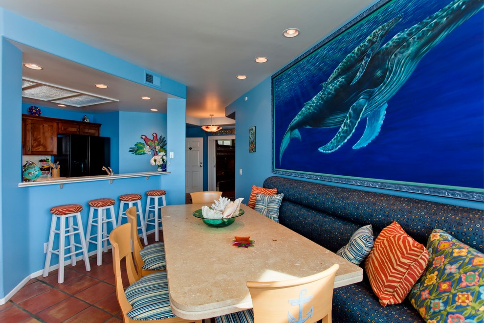 Small tropical open plan dining in San Diego with blue walls and terra-cotta floors.