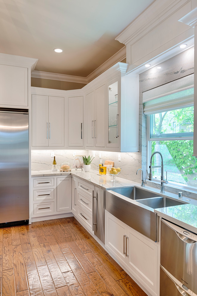 Example of a large transitional l-shaped medium tone wood floor eat-in kitchen design in Orange County with a drop-in sink, quartzite countertops, white backsplash, stone slab backsplash, stainless steel appliances, an island, beaded inset cabinets and white cabinets