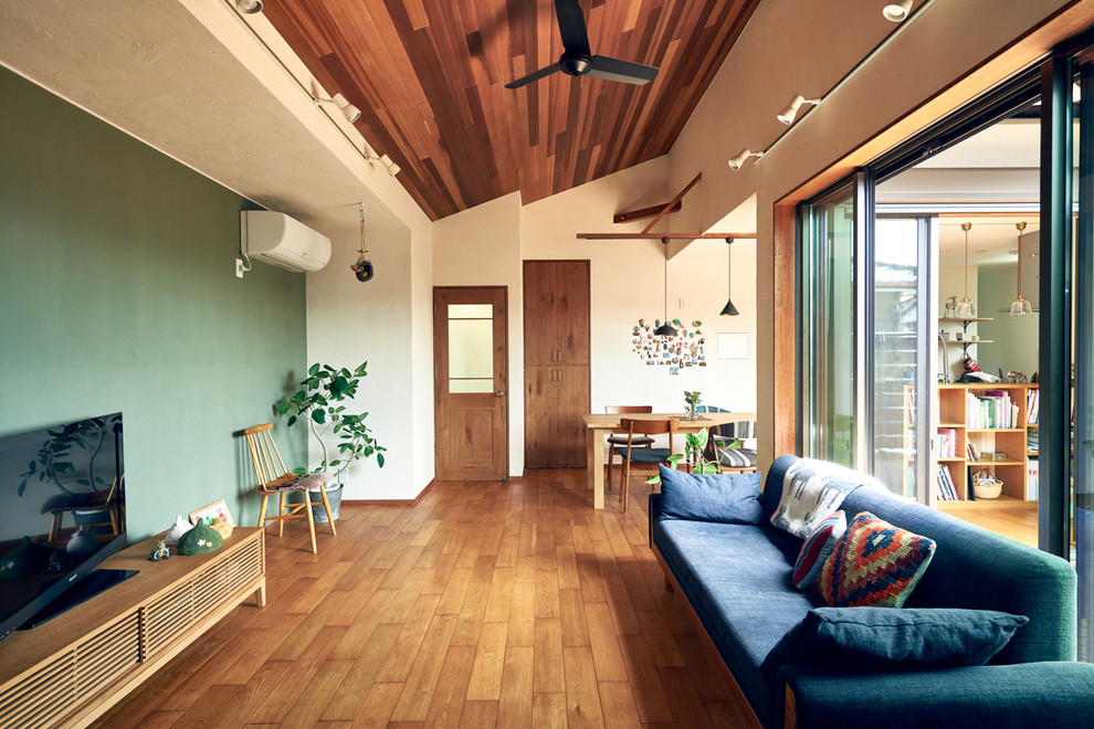 Photo of an eclectic living room in Nagoya with multi-coloured walls, medium hardwood floors, a freestanding tv and brown floor.