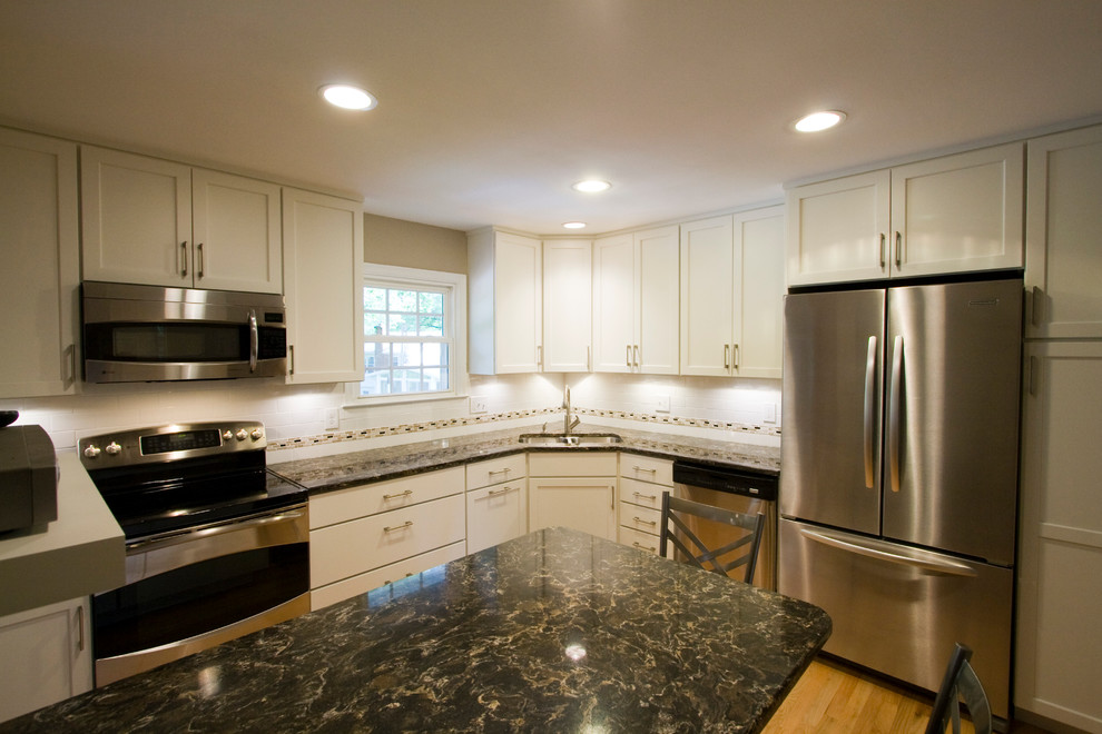 Inspiration for a large transitional l-shaped light wood floor enclosed kitchen remodel in DC Metro with an undermount sink, shaker cabinets, white cabinets, granite countertops, white backsplash, subway tile backsplash, stainless steel appliances and an island