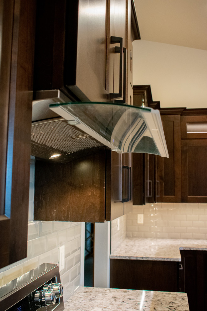 Large transitional l-shaped vinyl floor, brown floor and vaulted ceiling eat-in kitchen photo with an undermount sink, flat-panel cabinets, medium tone wood cabinets, quartz countertops, gray backsplash, ceramic backsplash, black appliances, an island and beige countertops