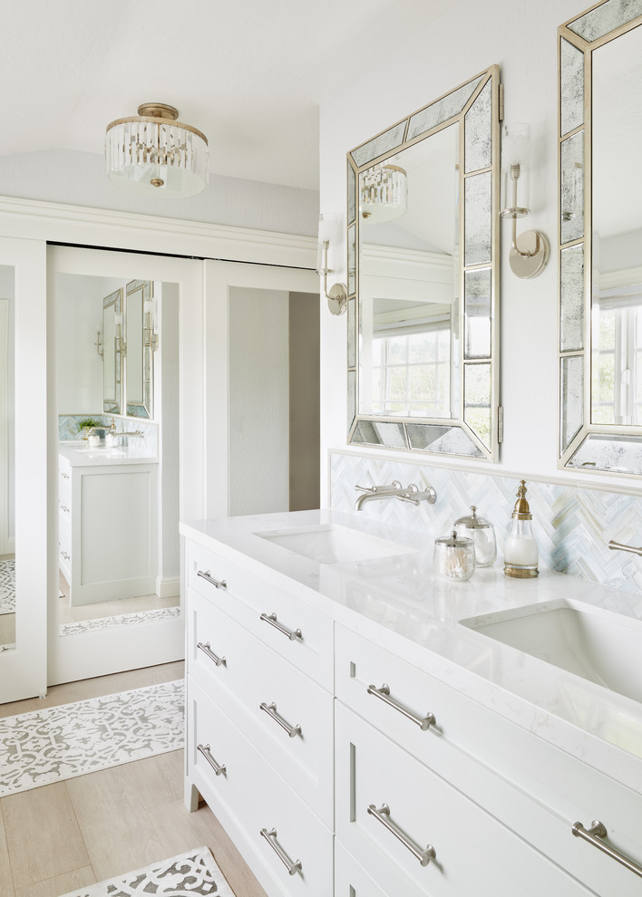 Example of a mid-sized beach style master gray tile and subway tile light wood floor and beige floor corner shower design in San Francisco with shaker cabinets, white cabinets, an undermount sink, quartzite countertops, a hinged shower door, white countertops and white walls