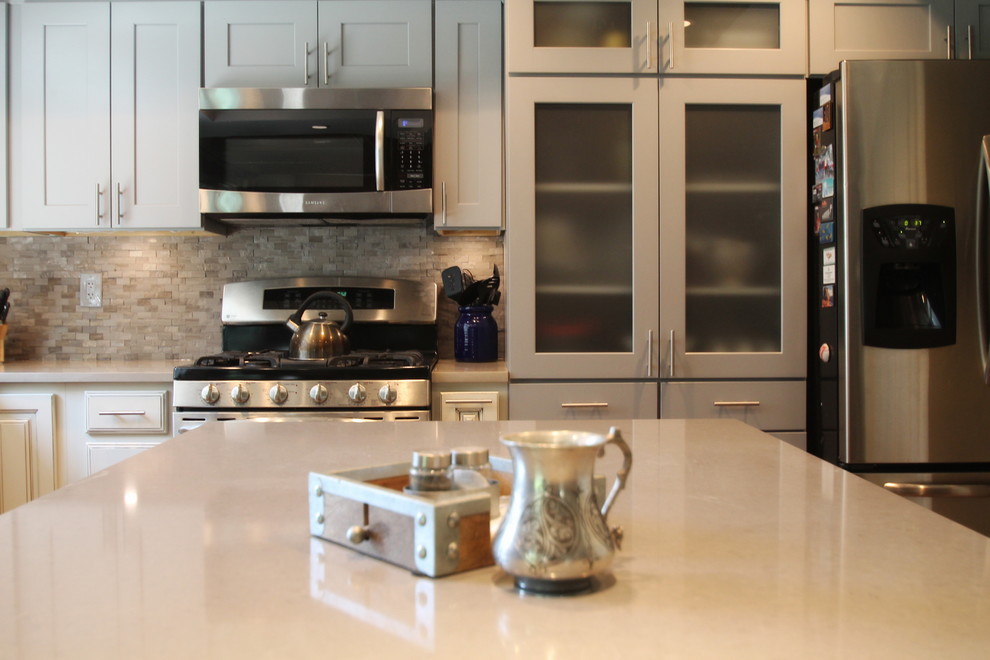 Example of a large transitional l-shaped medium tone wood floor eat-in kitchen design in Denver with an undermount sink, shaker cabinets, gray cabinets, quartz countertops, gray backsplash, stone tile backsplash, stainless steel appliances and an island