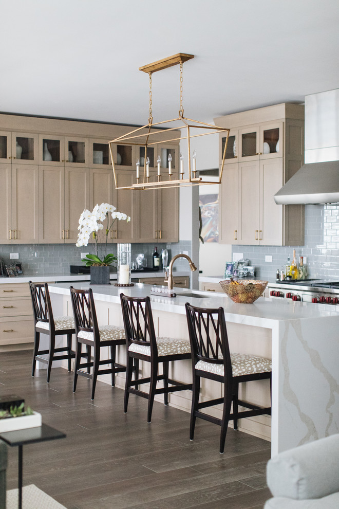 Inspiration for a large transitional u-shaped medium tone wood floor and brown floor kitchen remodel in Chicago with an undermount sink, shaker cabinets, beige cabinets, quartz countertops, glass tile backsplash, stainless steel appliances, an island and white countertops