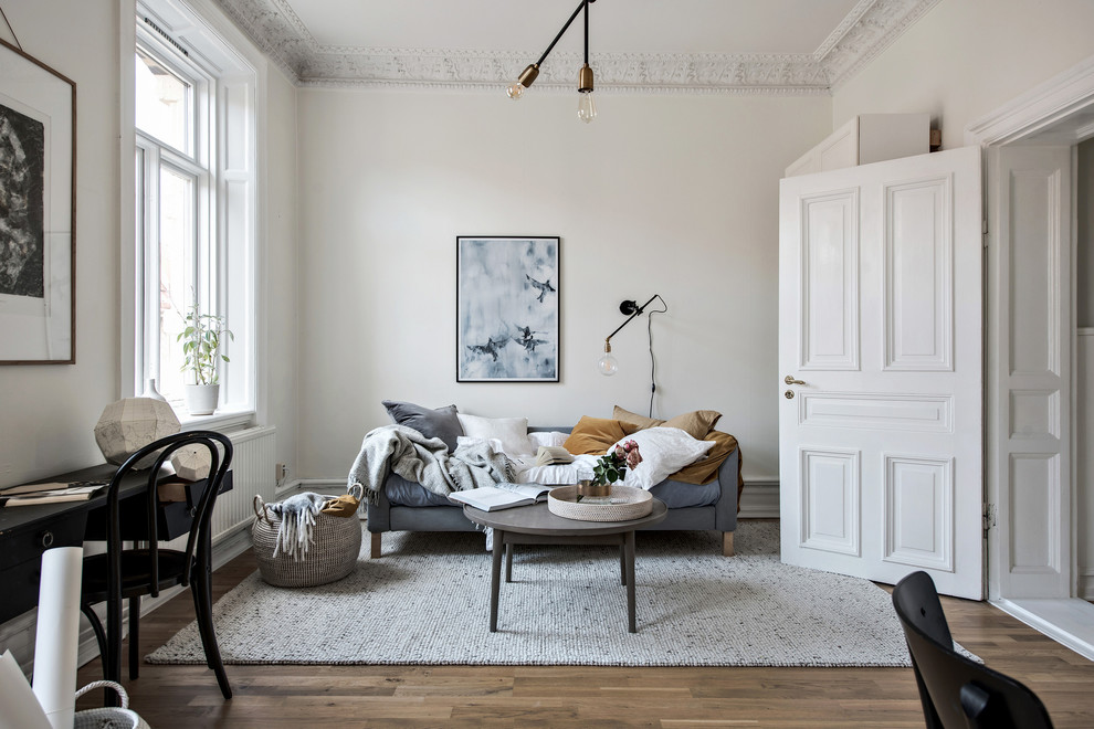 This is an example of a mid-sized scandinavian enclosed living room in Gothenburg with white walls, medium hardwood floors and no fireplace.