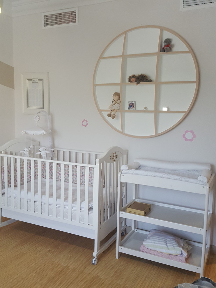 This is an example of a mid-sized transitional nursery for girls in Other with beige walls and linoleum floors.