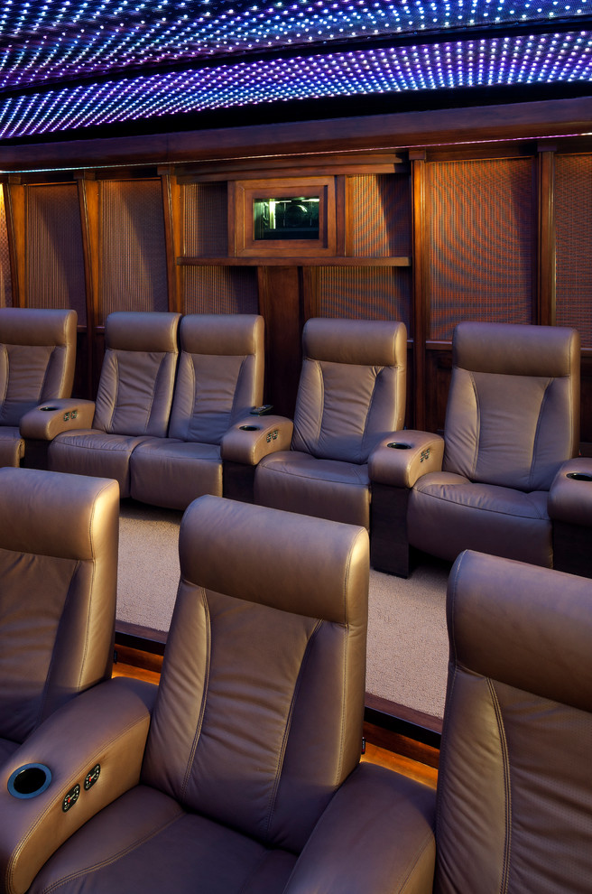 Large modern enclosed home theatre in Phoenix with brown walls, carpet and a projector screen.