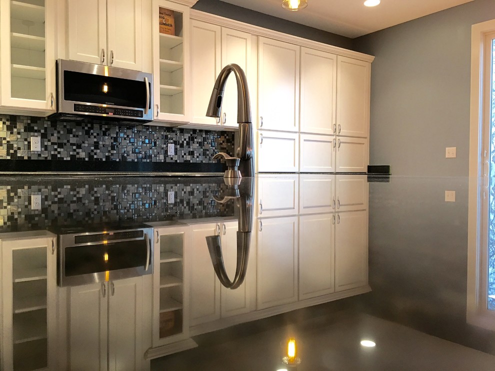 Large transitional l-shaped light wood floor eat-in kitchen photo with an undermount sink, recessed-panel cabinets, white cabinets, granite countertops, multicolored backsplash, glass tile backsplash, stainless steel appliances and an island