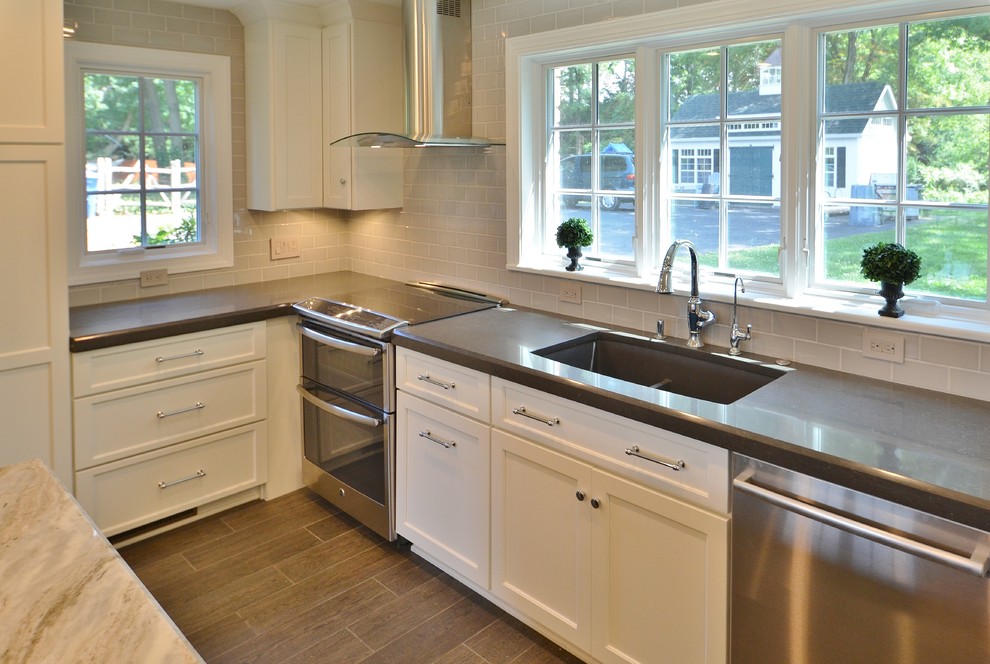 This is an example of a transitional eat-in kitchen in DC Metro with a single-bowl sink, flat-panel cabinets, white cabinets, quartz benchtops, glass tile splashback, stainless steel appliances, porcelain floors and with island.