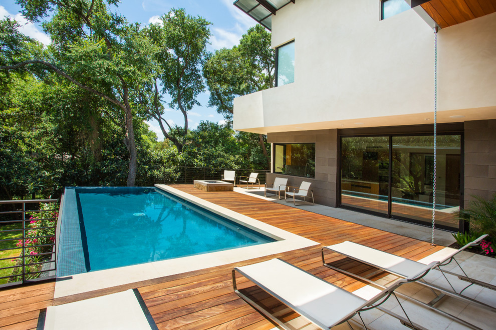 Mid-sized modern backyard rectangular infinity pool in Austin with decking.