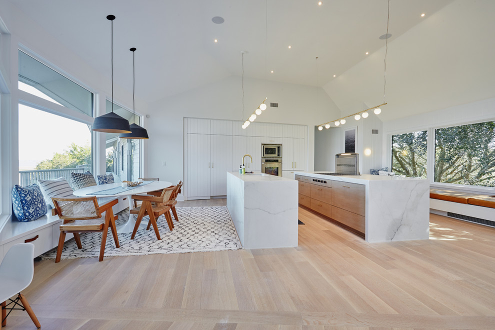 This is an example of a contemporary l-shaped eat-in kitchen in Other with stainless steel appliances, light hardwood floors, multiple islands, beige floor and flat-panel cabinets.