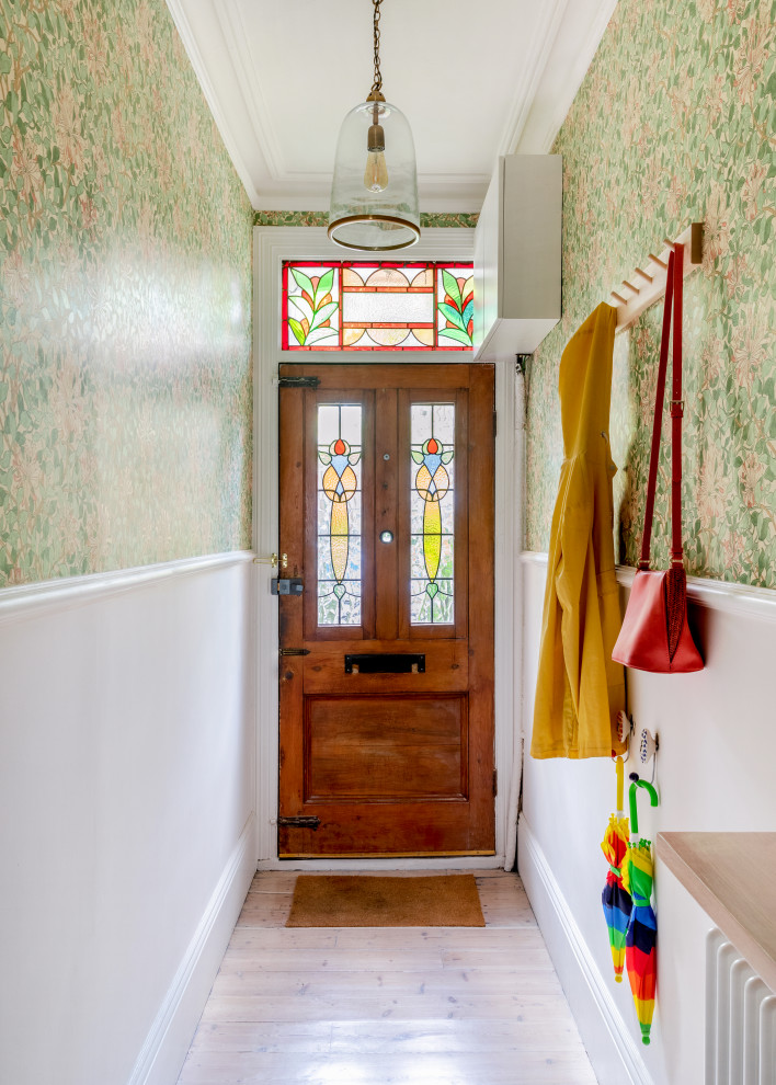 Modelo de hall tradicional con paredes marrones, suelo de madera clara, puerta simple, puerta de madera en tonos medios, suelo marrón y papel pintado