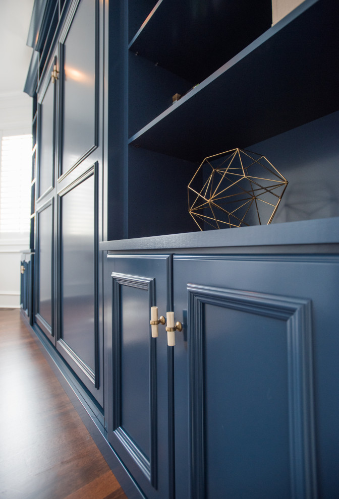 Inspiration for a mid-sized transitional gender-neutral storage and wardrobe in Denver with recessed-panel cabinets, blue cabinets, laminate floors, brown floor and vaulted.