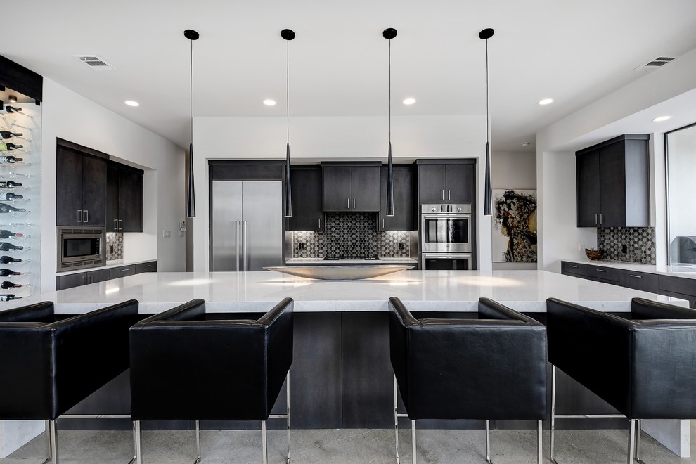 This is an example of a large contemporary kitchen in Austin with flat-panel cabinets, quartz benchtops, stainless steel appliances, concrete floors, with island, grey floor, white benchtop and black splashback.