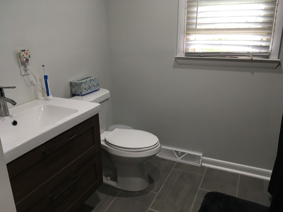 Small transitional 3/4 porcelain tile and gray floor bathroom photo with dark wood cabinets, a one-piece toilet, gray walls and an integrated sink