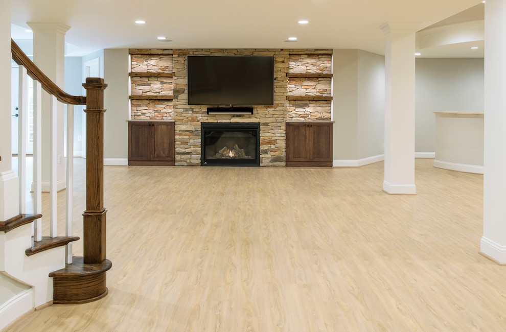 Transitional walk-out vinyl floor and beige floor basement photo in DC Metro with beige walls, a standard fireplace and a stone fireplace