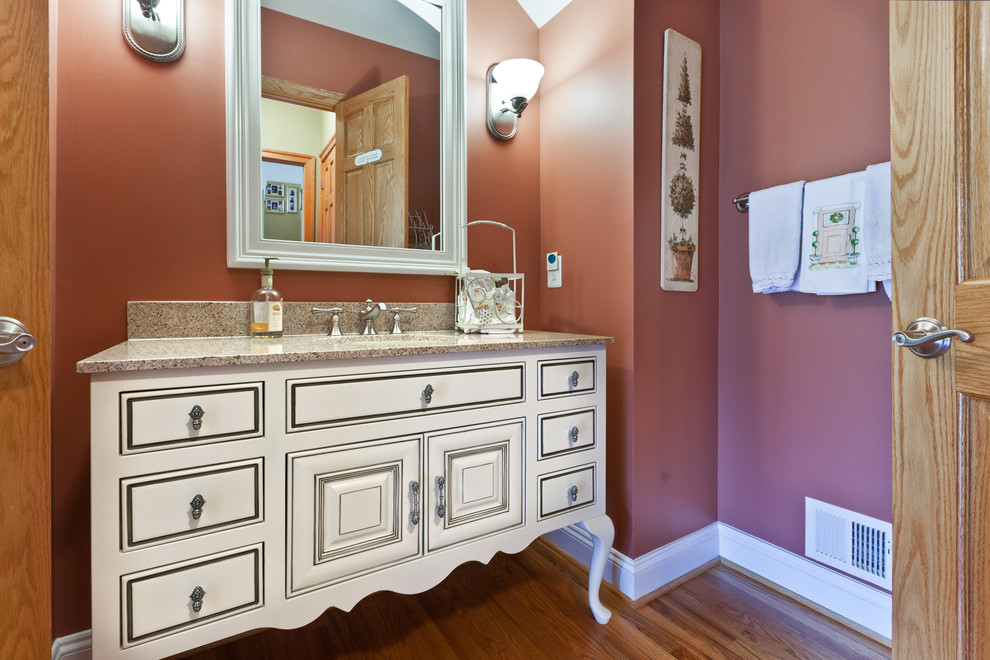 Traditional bathroom in DC Metro with beaded inset cabinets, white cabinets, red walls, medium hardwood floors, an undermount sink and granite benchtops.
