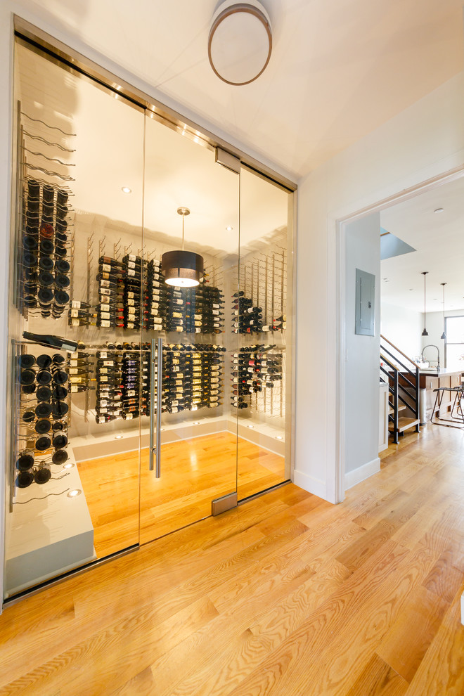 This is an example of a large contemporary wine cellar in New York with light hardwood floors, display racks and yellow floor.