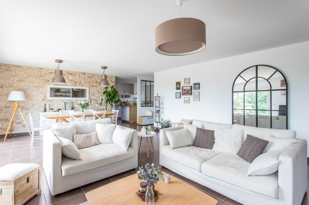 Inspiration for a large country open concept family room in Lyon with white walls, ceramic floors, a standard fireplace, a plaster fireplace surround and brown floor.