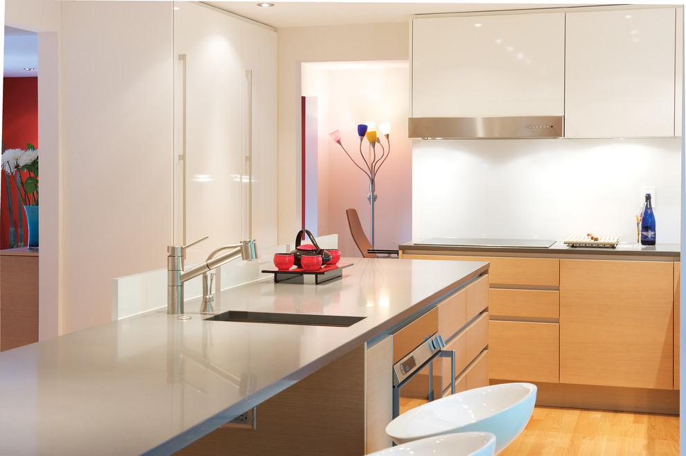 Design ideas for a modern l-shaped eat-in kitchen in DC Metro with an integrated sink, flat-panel cabinets, white cabinets, quartz benchtops, white splashback, glass sheet splashback, panelled appliances, light hardwood floors and with island.