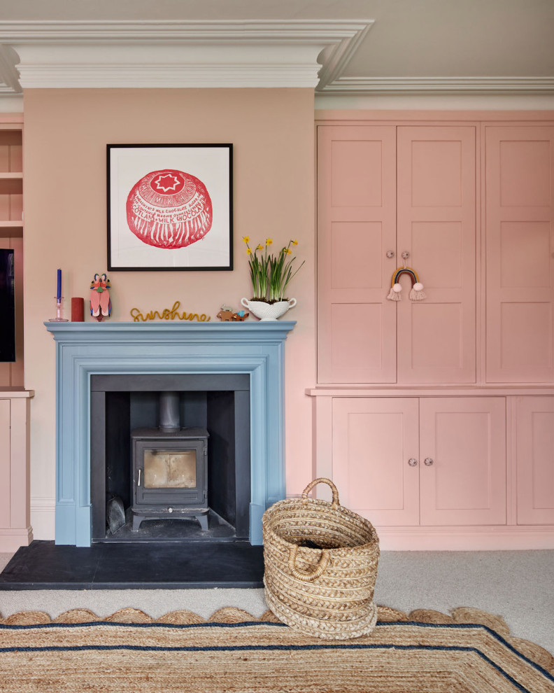 Foto de salón clásico de tamaño medio con paredes rosas, moqueta, estufa de leña, marco de chimenea de madera y suelo beige