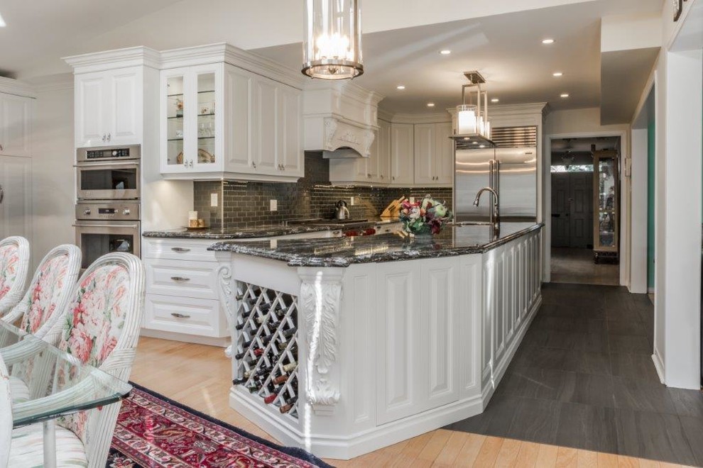 Eat-in kitchen - large traditional l-shaped ceramic tile eat-in kitchen idea in Toronto with a double-bowl sink, raised-panel cabinets, white cabinets, granite countertops, metallic backsplash, metal backsplash, stainless steel appliances and an island