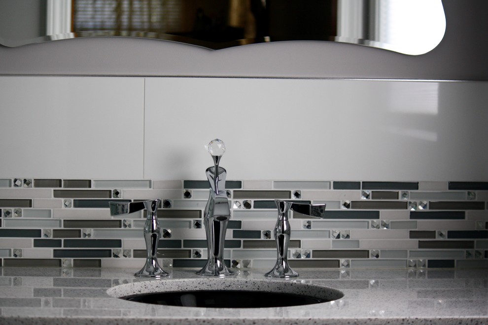 Example of a transitional master multicolored tile and glass tile porcelain tile and white floor home design design with furniture-like cabinets, black cabinets, a two-piece toilet, gray walls, an undermount sink, quartz countertops, a hinged shower door and white countertops