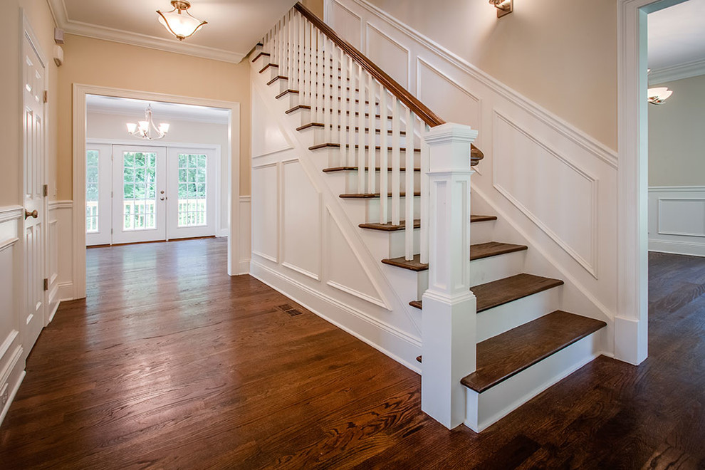 This is an example of a large transitional wood straight staircase in Other with painted wood risers and wood railing.