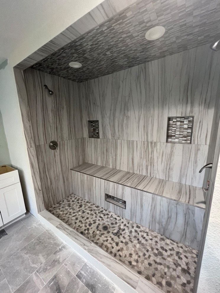Réalisation d'une grande salle de bain principale design avec une baignoire posée, une douche double, un carrelage gris, un carrelage de pierre, un sol en carrelage de céramique, un sol gris, un banc de douche et meuble-lavabo sur pied.