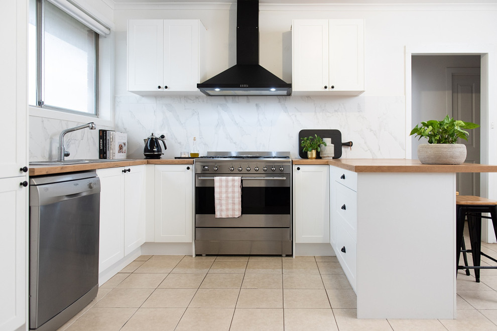 This is an example of a mid-sized scandinavian u-shaped kitchen pantry in Melbourne with a double-bowl sink, open cabinets, white cabinets, laminate benchtops, grey splashback, ceramic splashback, black appliances, cement tiles, with island and white floor.