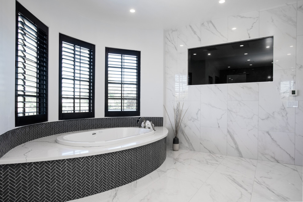 This is an example of an expansive modern master bathroom in Los Angeles with flat-panel cabinets, white cabinets, a hot tub, an open shower, a bidet, gray tile, glass tile, white walls, marble floors, a wall-mount sink, engineered quartz benchtops, white floor, a hinged shower door and white benchtops.