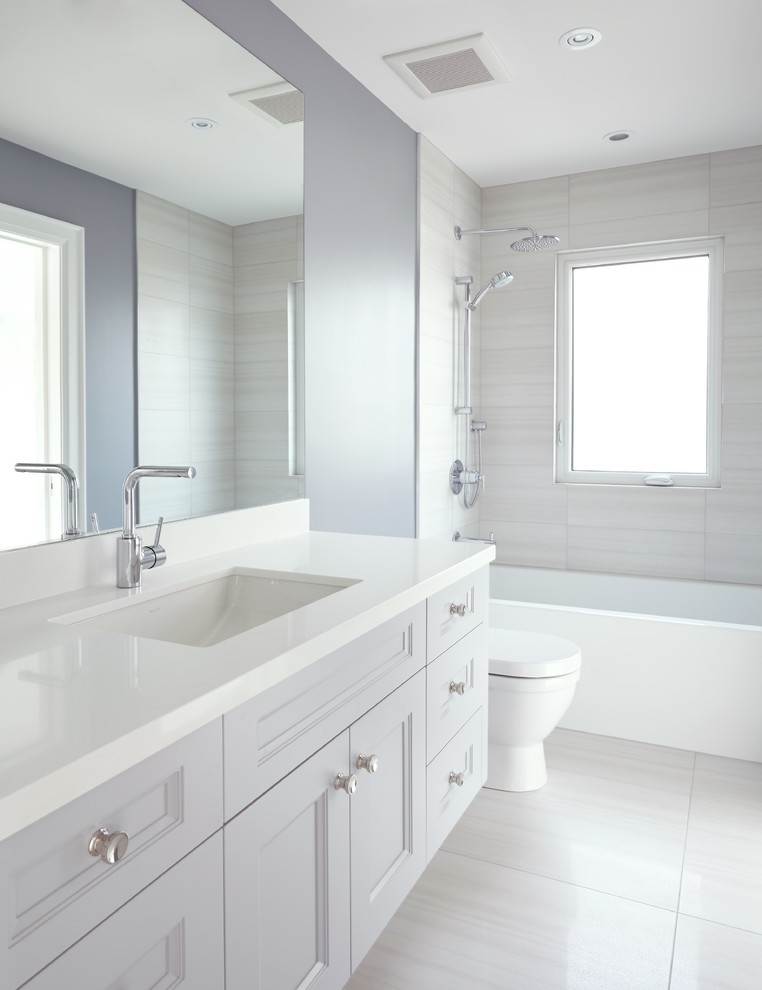 Small transitional bathroom in Toronto with an undermount sink, medium wood cabinets, engineered quartz benchtops, an alcove tub, a shower/bathtub combo, beige tile, ceramic tile, porcelain floors, blue walls and recessed-panel cabinets.