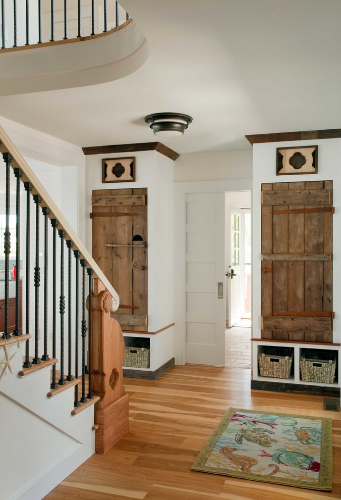 This is an example of a transitional foyer in Boston with white walls, light hardwood floors and a white front door.