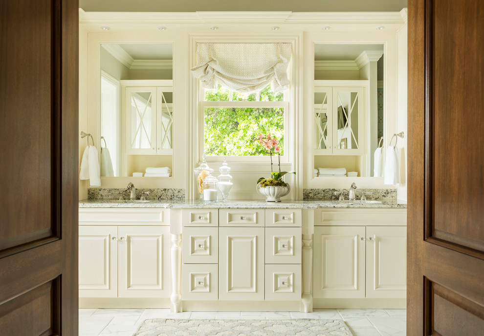 Inspiration for a large traditional master bathroom in Other with raised-panel cabinets, white cabinets, granite benchtops, a freestanding tub, an alcove shower, a two-piece toilet, beige walls, marble floors and an undermount sink.