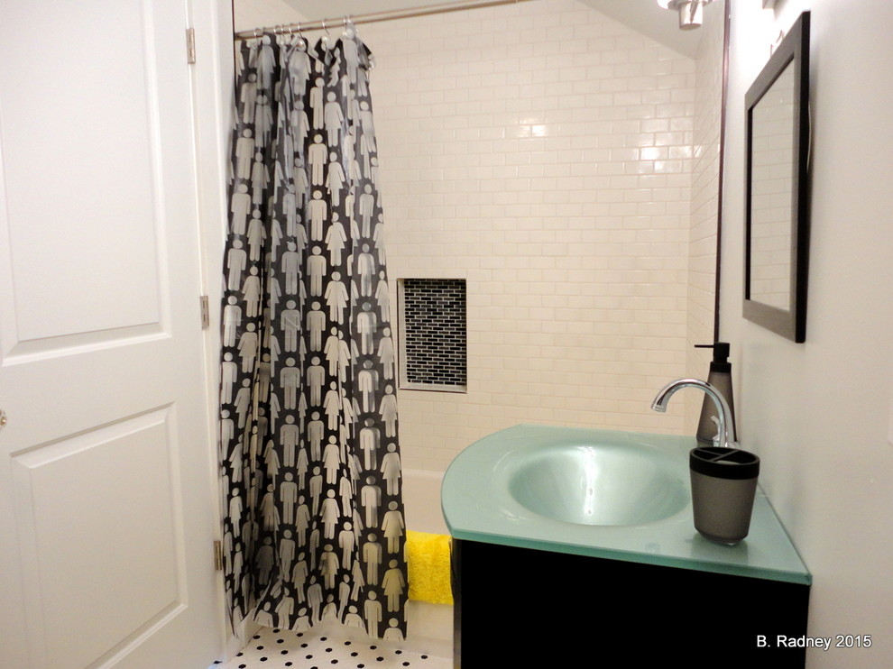 This is an example of a mid-sized contemporary kids bathroom in Other with flat-panel cabinets, black cabinets, a drop-in tub, a shower/bathtub combo, a two-piece toilet, black and white tile, subway tile, white walls, mosaic tile floors, a console sink and glass benchtops.