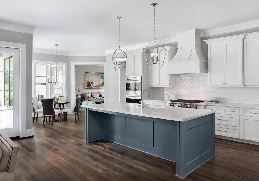Inspiration for a large transitional open plan kitchen in Houston with white cabinets, quartzite benchtops, white splashback, subway tile splashback, stainless steel appliances, dark hardwood floors, with island, brown floor, white benchtop, an undermount sink and shaker cabinets.