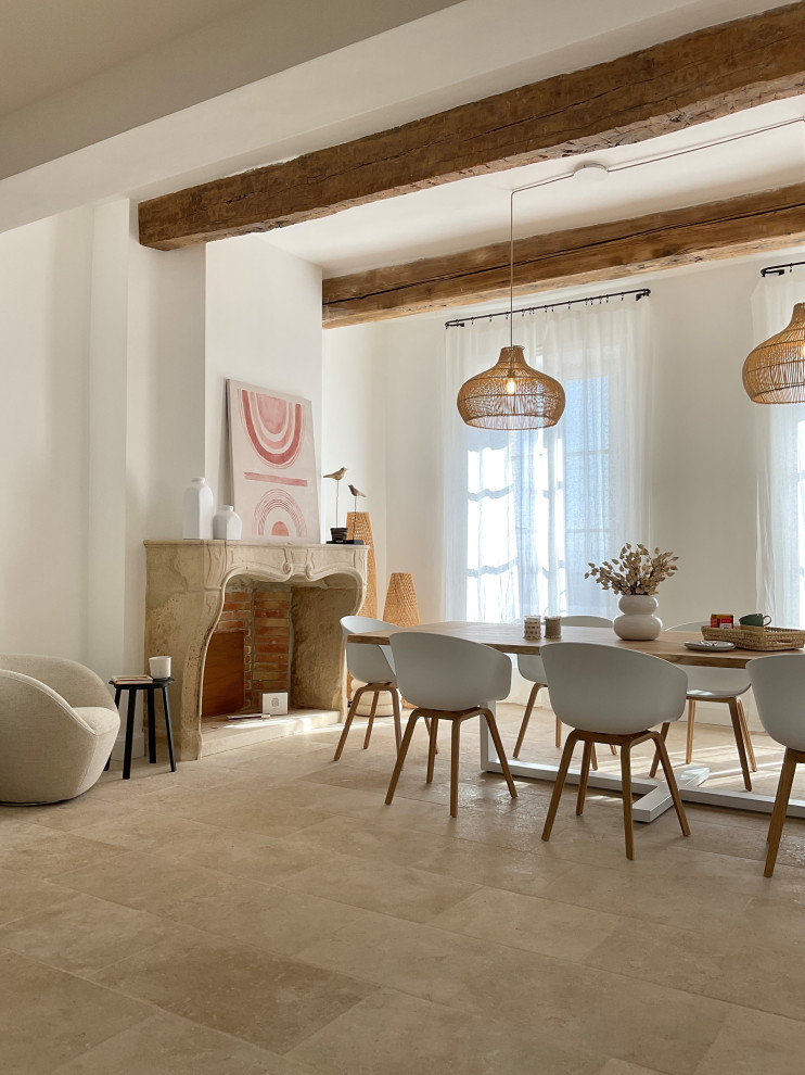 Photo of a large mediterranean open plan dining in Marseille with white walls, travertine floors, a standard fireplace, a stone fireplace surround, beige floor and exposed beam.