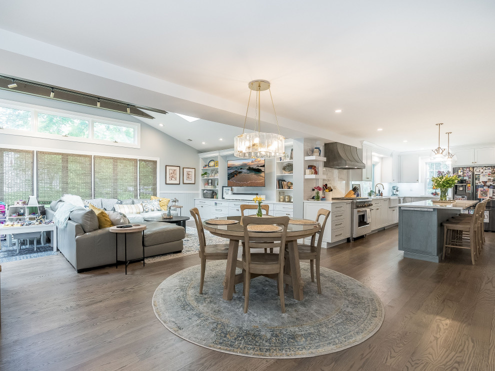 Expansive transitional kitchen/dining combo in New York with blue walls, medium hardwood floors, a standard fireplace, a stone fireplace surround, grey floor, exposed beam and planked wall panelling.