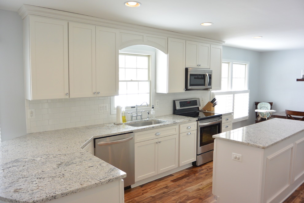 Mid-sized transitional u-shaped medium tone wood floor and brown floor eat-in kitchen photo in Baltimore with an undermount sink, recessed-panel cabinets, white cabinets, granite countertops, white backsplash, subway tile backsplash, stainless steel appliances and an island