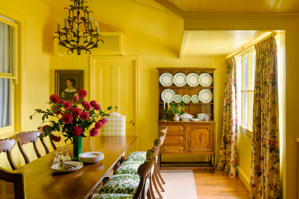 Réalisation d'une salle à manger champêtre avec un mur jaune, un sol en bois brun, un sol marron, un plafond voûté et du lambris de bois.