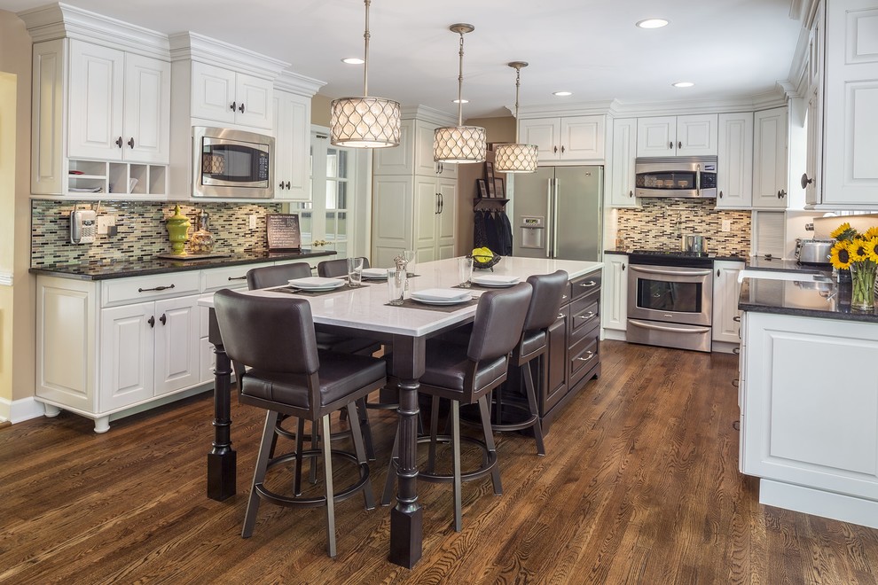 This is an example of a country u-shaped kitchen in Baltimore with a farmhouse sink, raised-panel cabinets, white cabinets, multi-coloured splashback, mosaic tile splashback, stainless steel appliances, dark hardwood floors, with island and brown floor.